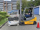 Eine Frau in Einsatzkleidung sitzt in einem Gabelstapler vor einer Gitterbox.