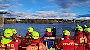 Menschen in Einsatzkleidung stehen vor einem Gewässer.