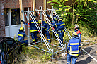 Einsatzkräfte des Technischen Hilfswerks errichten eine Stützkonstruktion an einem Haus.