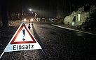 Ein Warnschild steht auf einer dunklen Straße. Darauf steht das Wort "Einsatz". 