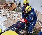 Mehrere Einsatzkräfte tragen einen Verletztendarsteller auf einer Trage.