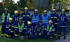 Eine Gruppe von Einsatzkräften posiert vor Bäumen.