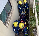 Vier Einsatzkräfte tragen einen Verletztendarsteller auf einer Kellertreppe aus dem Gebäude heraus.